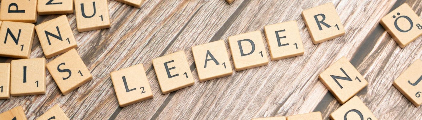 Wooden Scrabble tiles on a table spelling 'Leader' symbolize leadership and strategy.